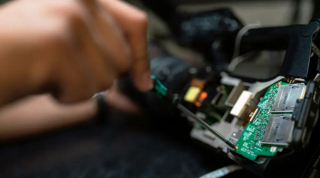 asmuo, laikantis žalią ir juodą elektroninę plokštę
